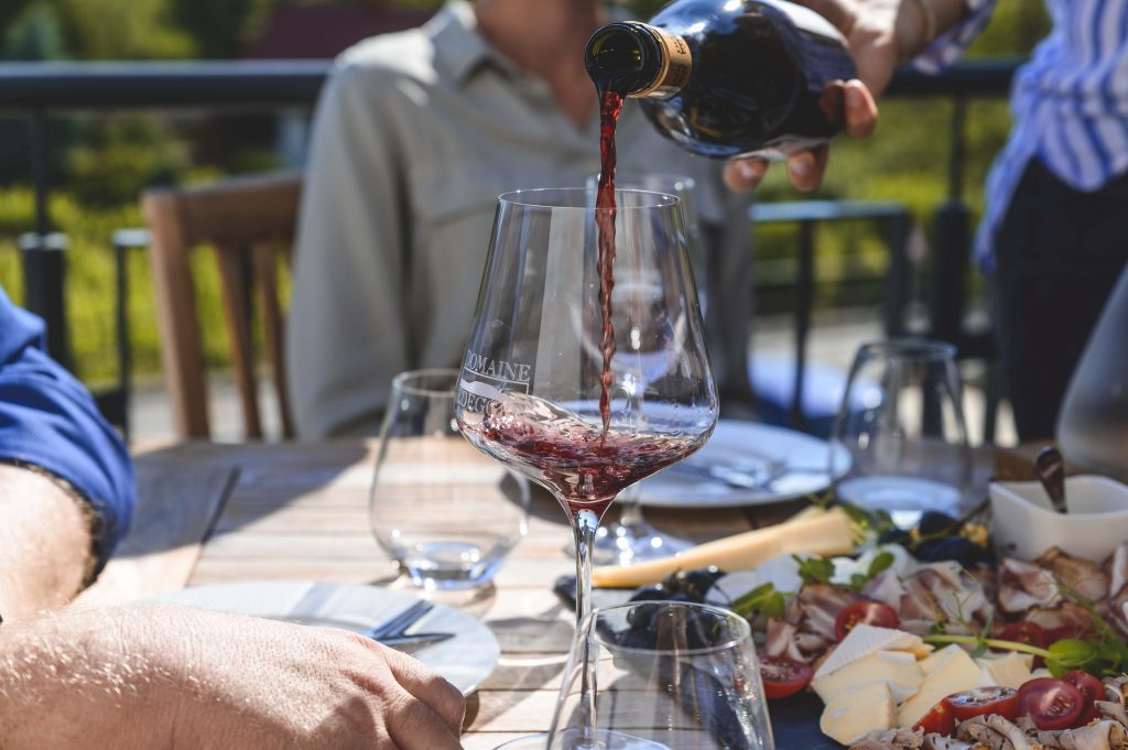 pouring wine into glass pouring wine into glass with cheese plate and ham plate